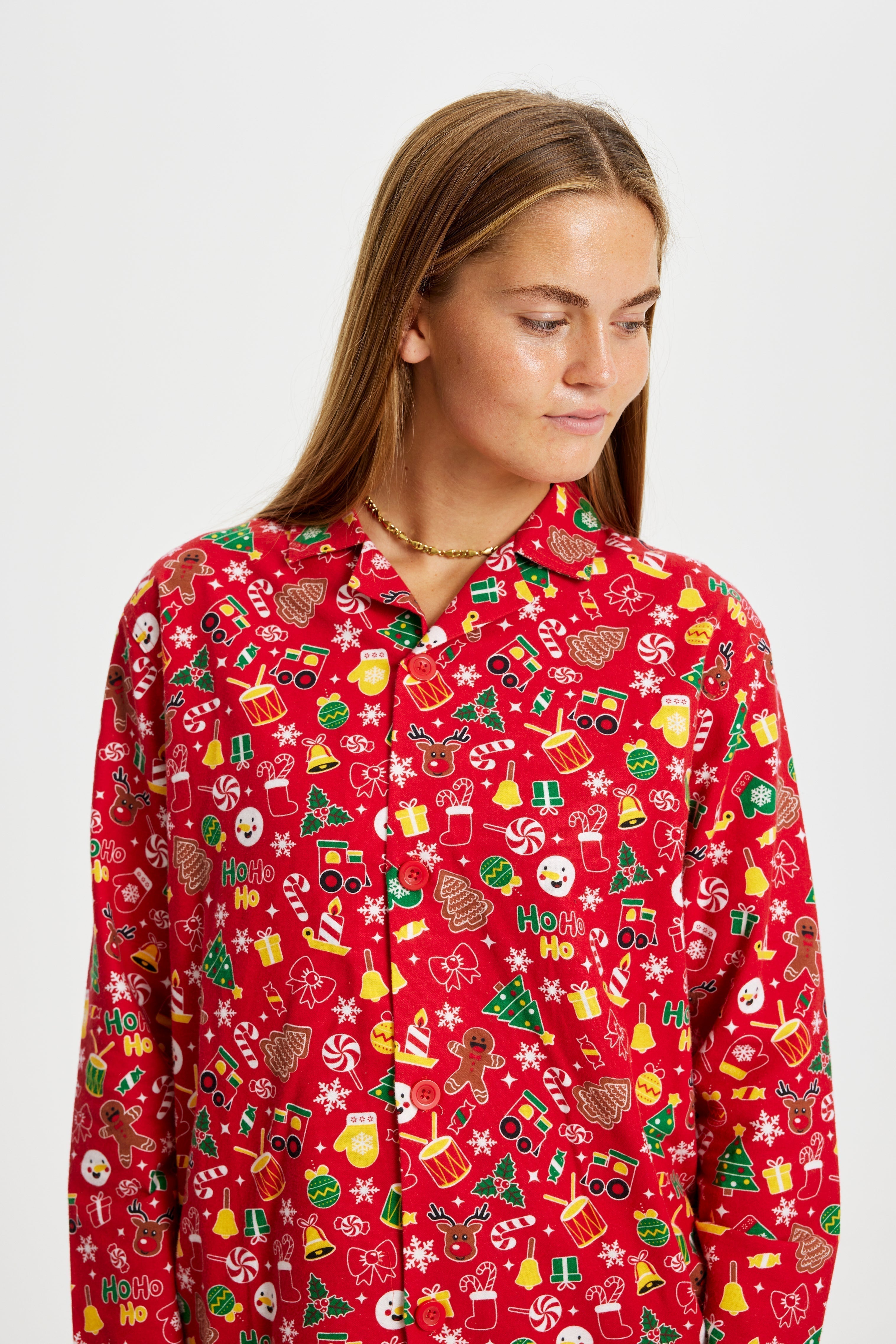 Une femme regardant de côté portant un pyjama de Noël rouge avec un imprimé de Noël.